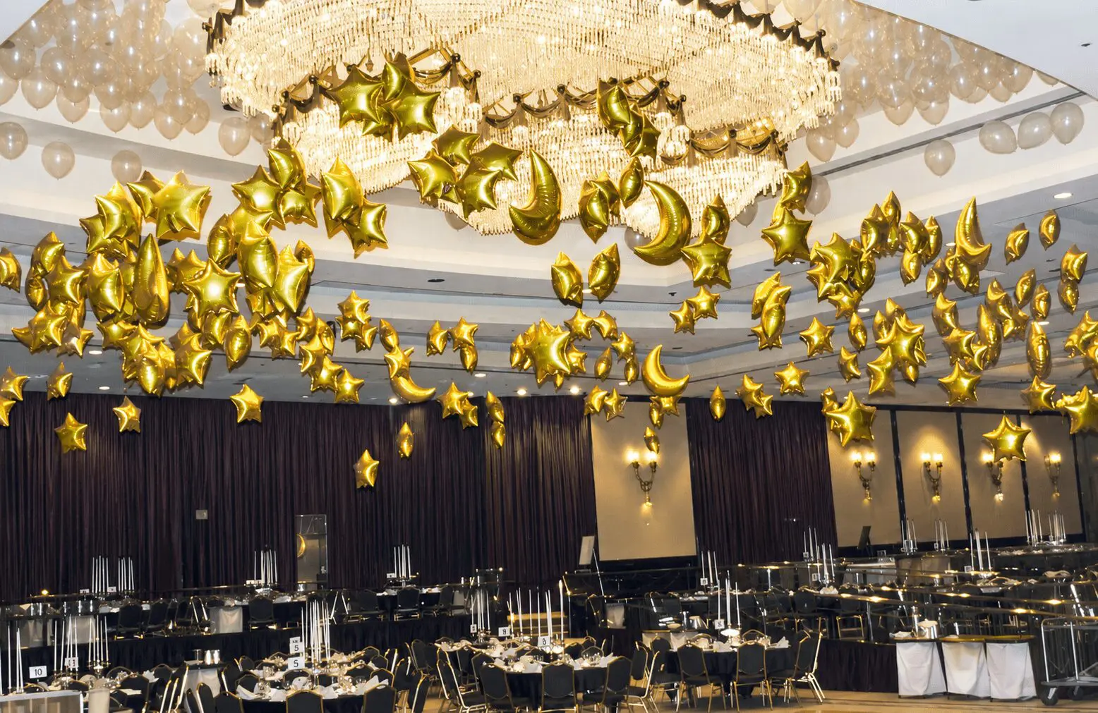 Golden star and crescent balloons beneath chandelier