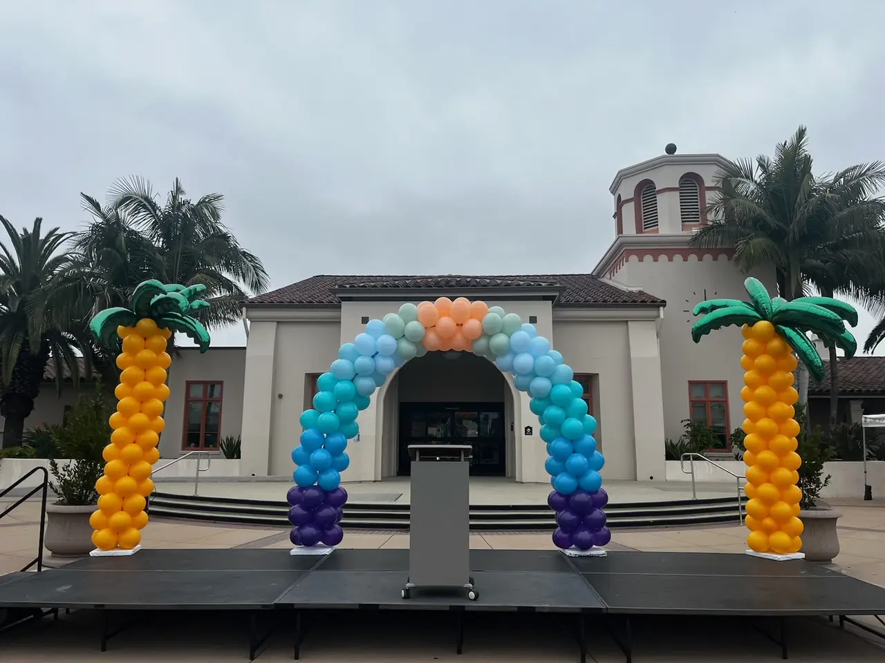 Colorful balloon arch and palm columns on stage