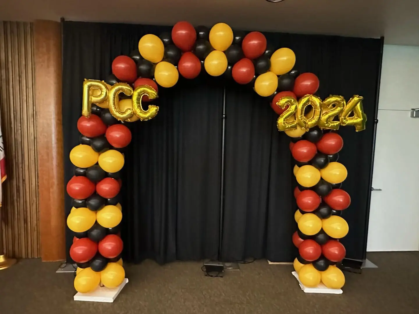 Red yellow black balloon arch reading PCC 2024