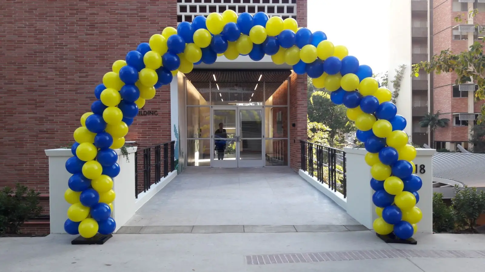 Blue and yellow balloon arch at building entrance