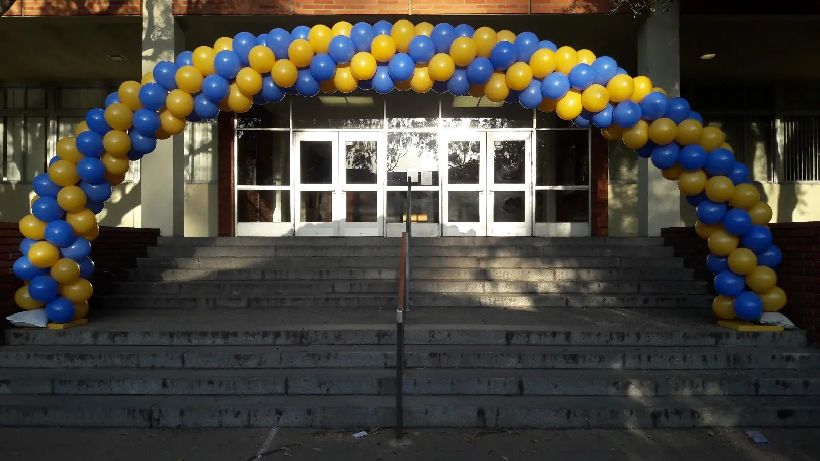 Blue and yellow balloon arch at building entrance