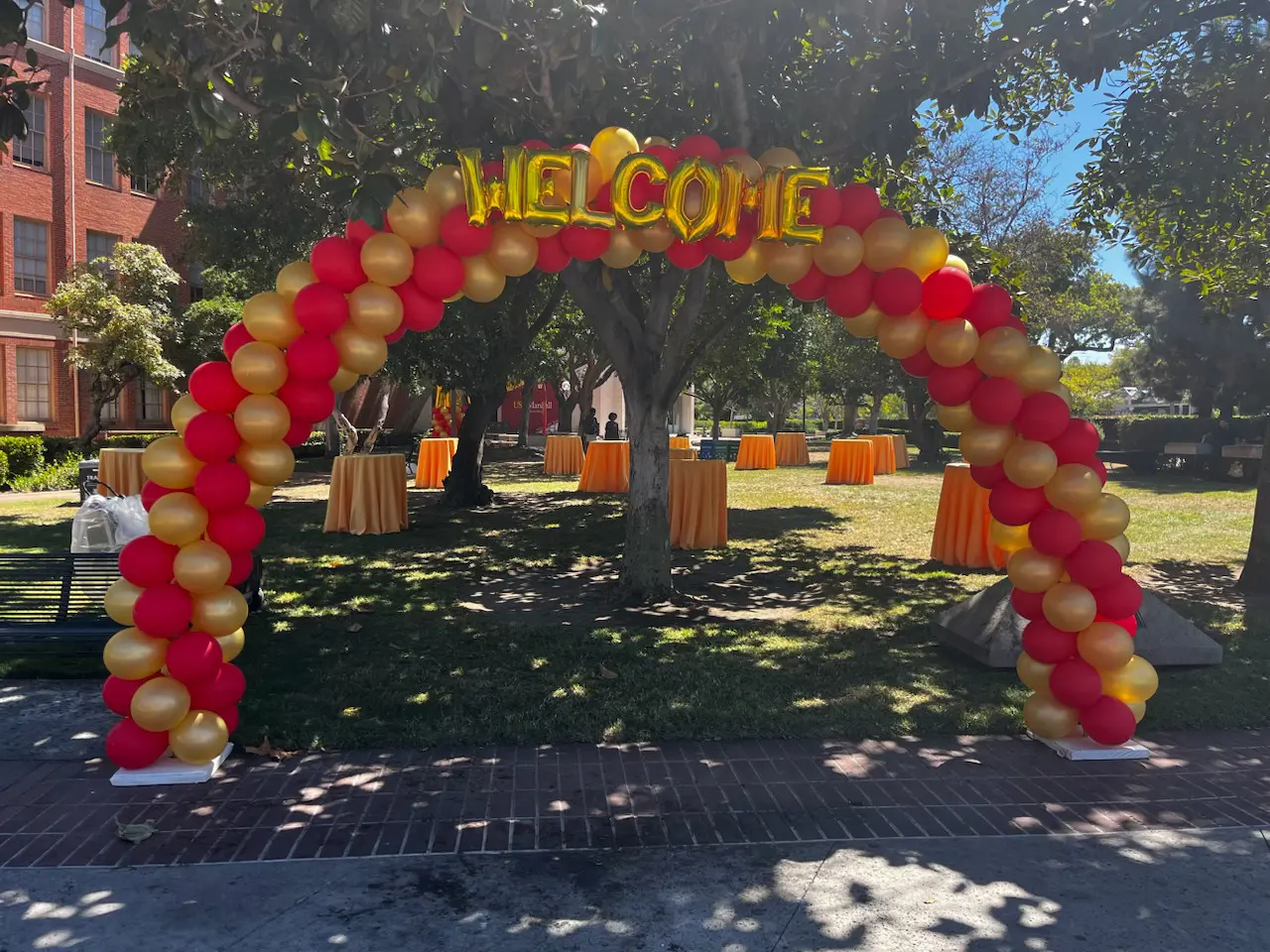 Red and gold welcome balloon arch outdoors