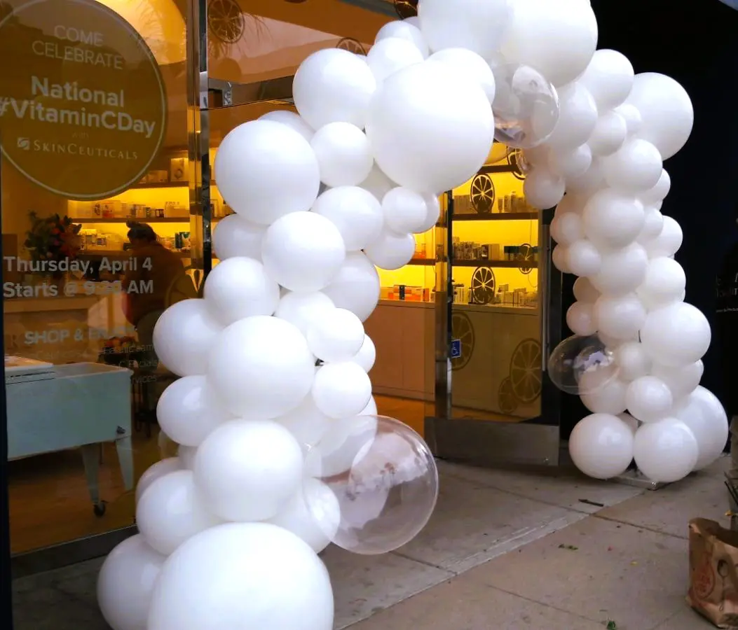 White balloon arch with clear balloons at storefront