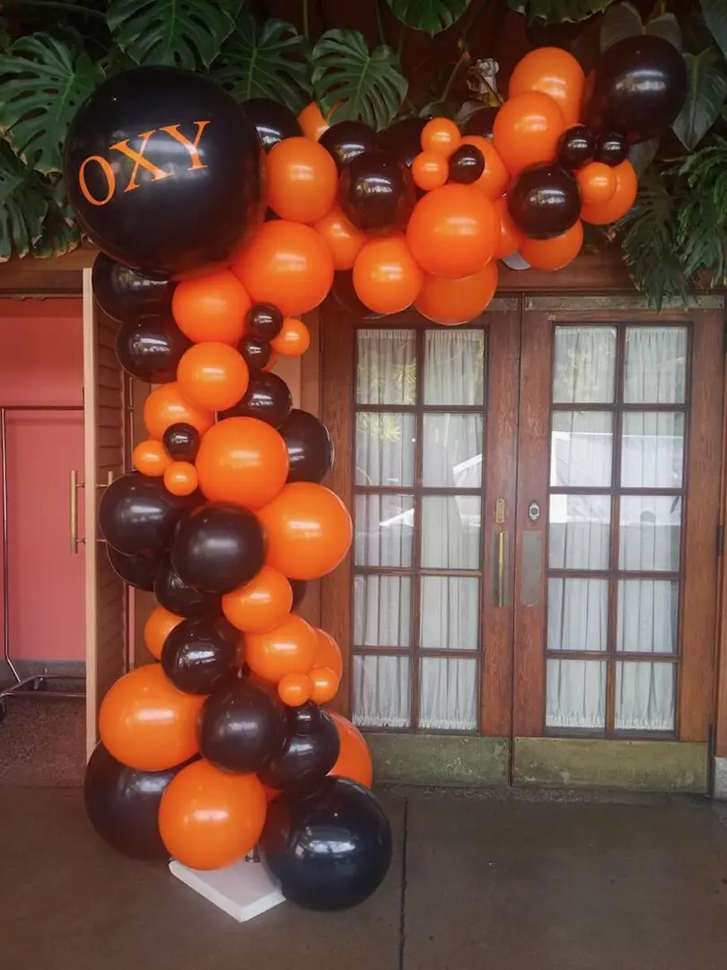 Orange and black balloon arch by doorway