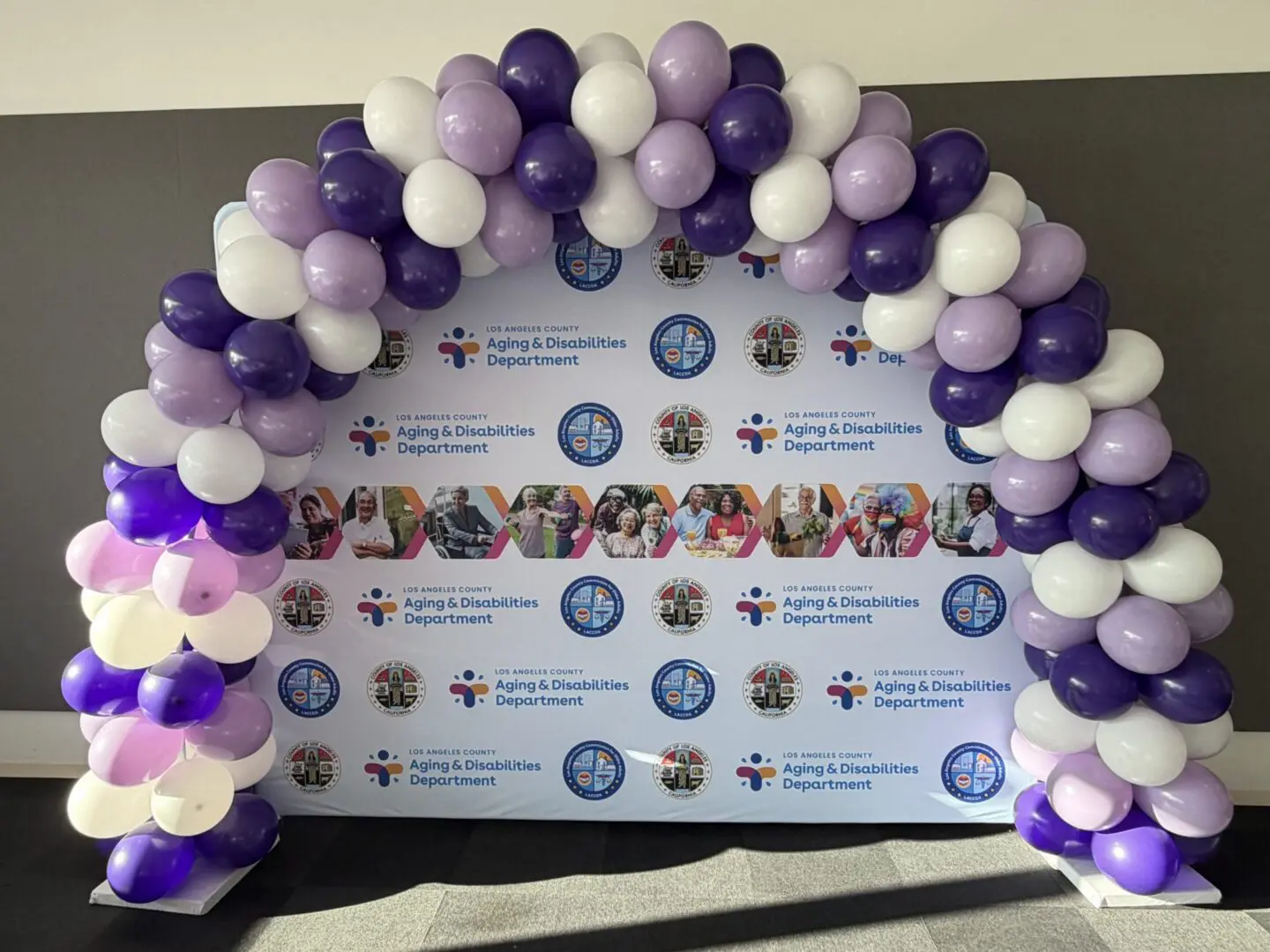 Purple and white balloon arch at event backdrop