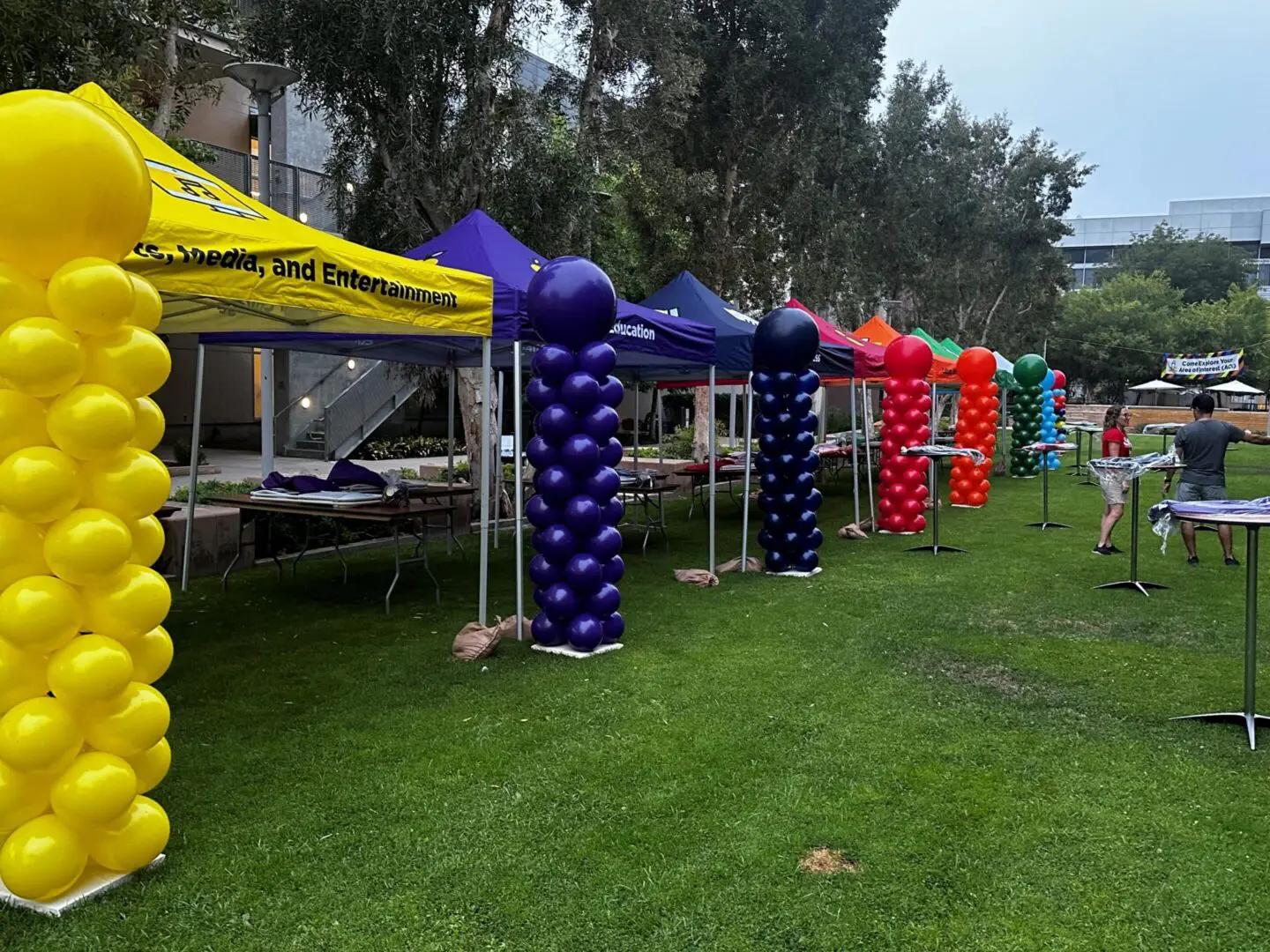 Colorful balloon columns lining outdoor event tents