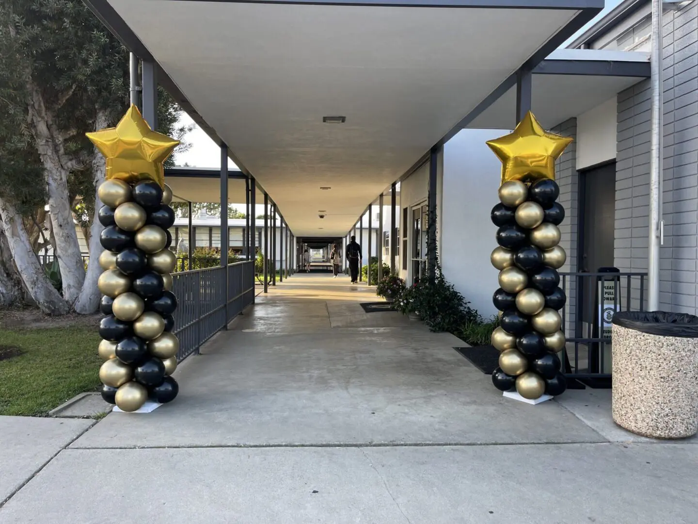 Covered corridor flanked by black and gold balloons