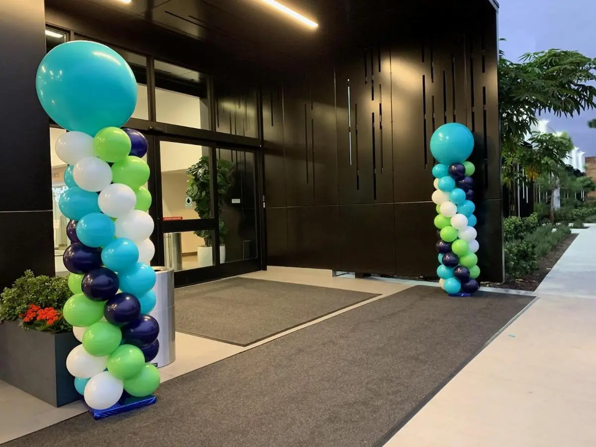 Two colorful balloon columns flanking building entrance