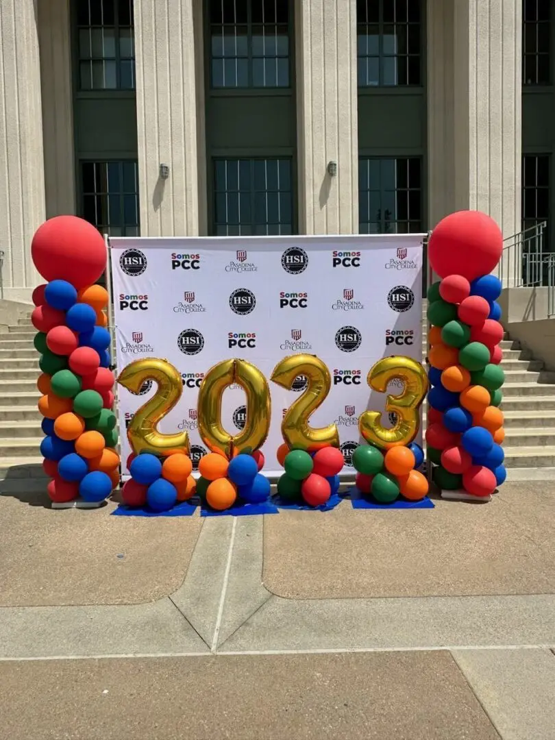 Gold "2023" balloons with colorful balloon columns