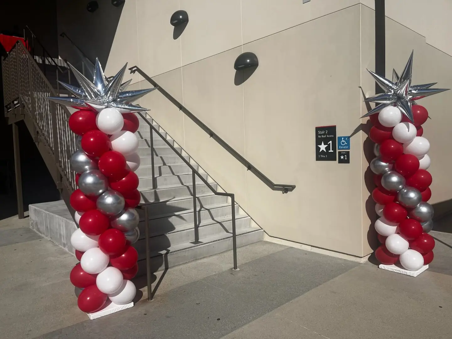 Red white silver balloon columns flanking outdoor stairs