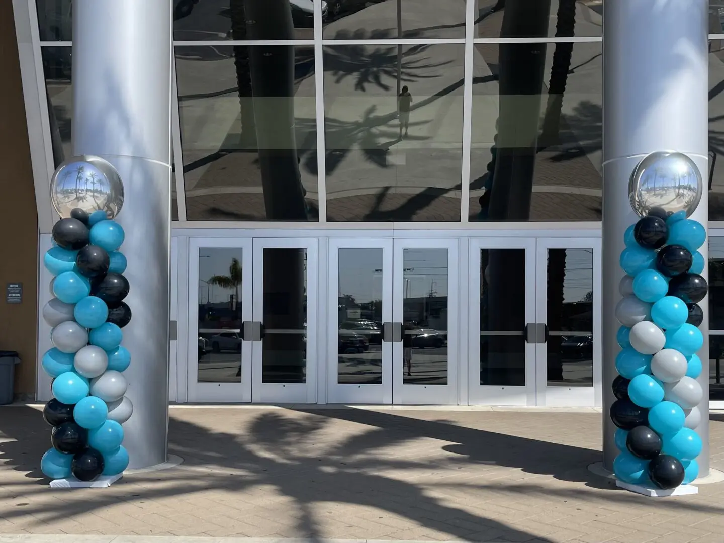 Glass doors flanked by teal and black balloons