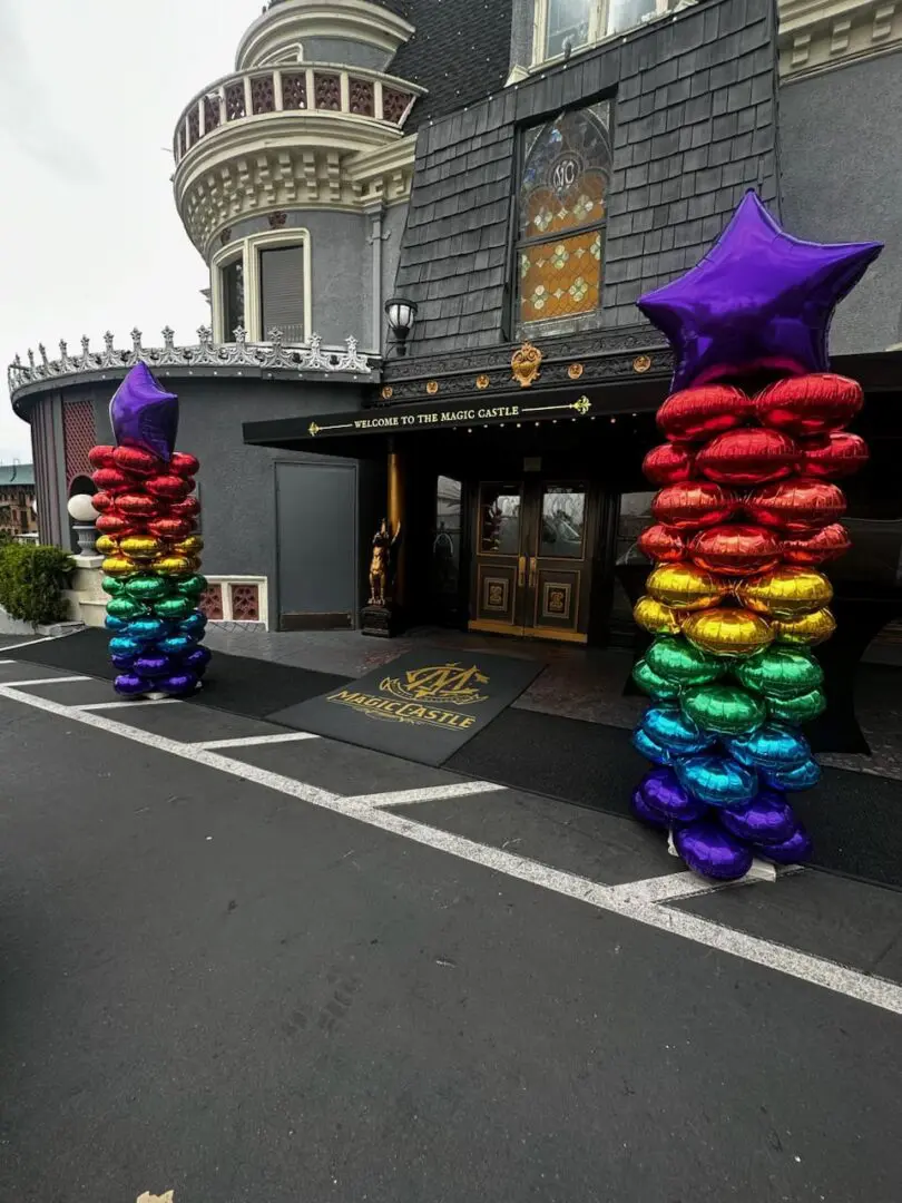 Rainbow balloon columns flanking castle entrance