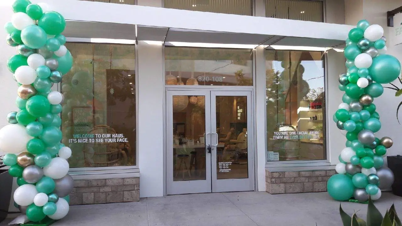 Storefront entrance decorated with green balloon columns