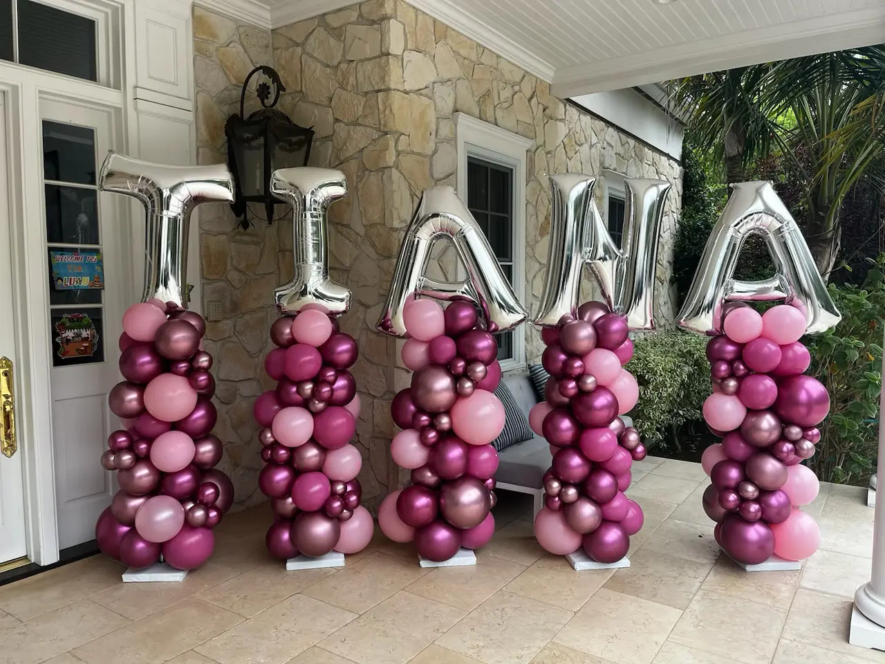 Pink and purple balloon columns spelling TIANA