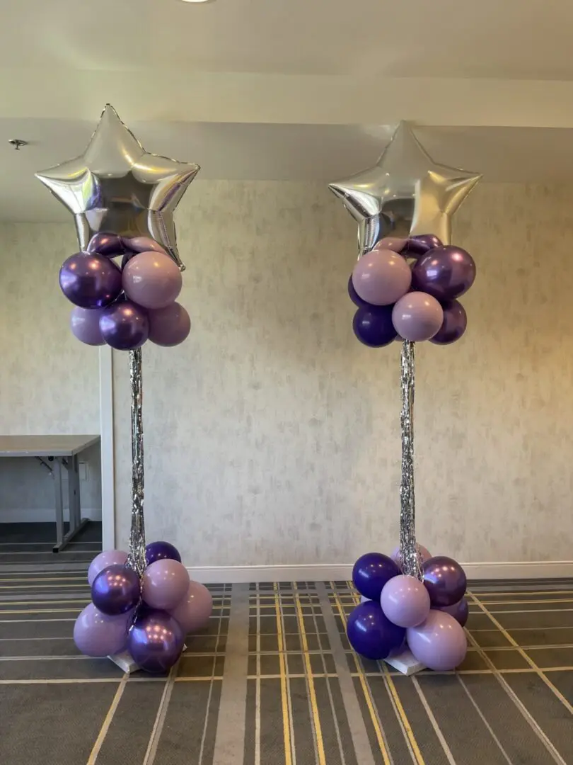 Two purple balloon columns topped with silver stars