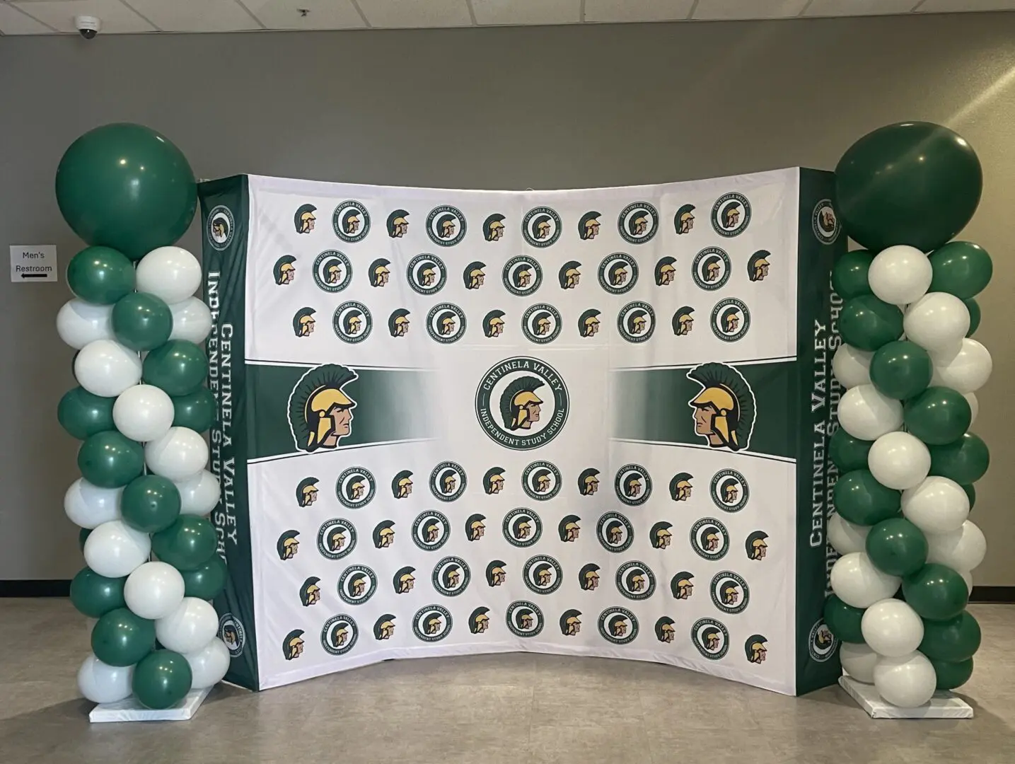 Green and white balloon columns with logo backdrop