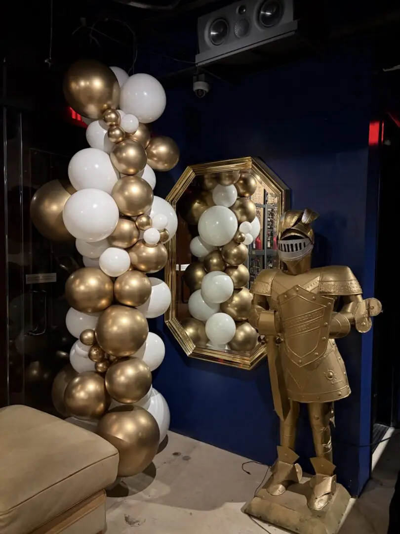 Gold and white balloon display beside golden knight