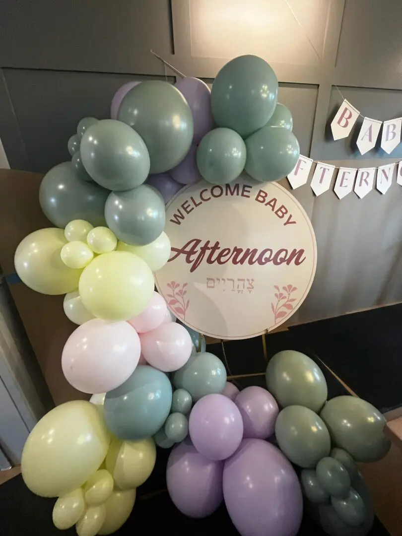 Pastel balloon arch around baby shower sign