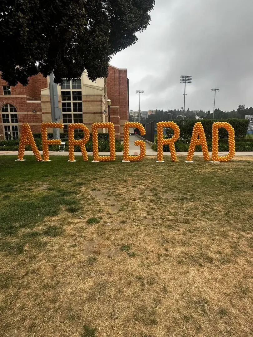 Large orange balloon letters spelling AFROGRAD
