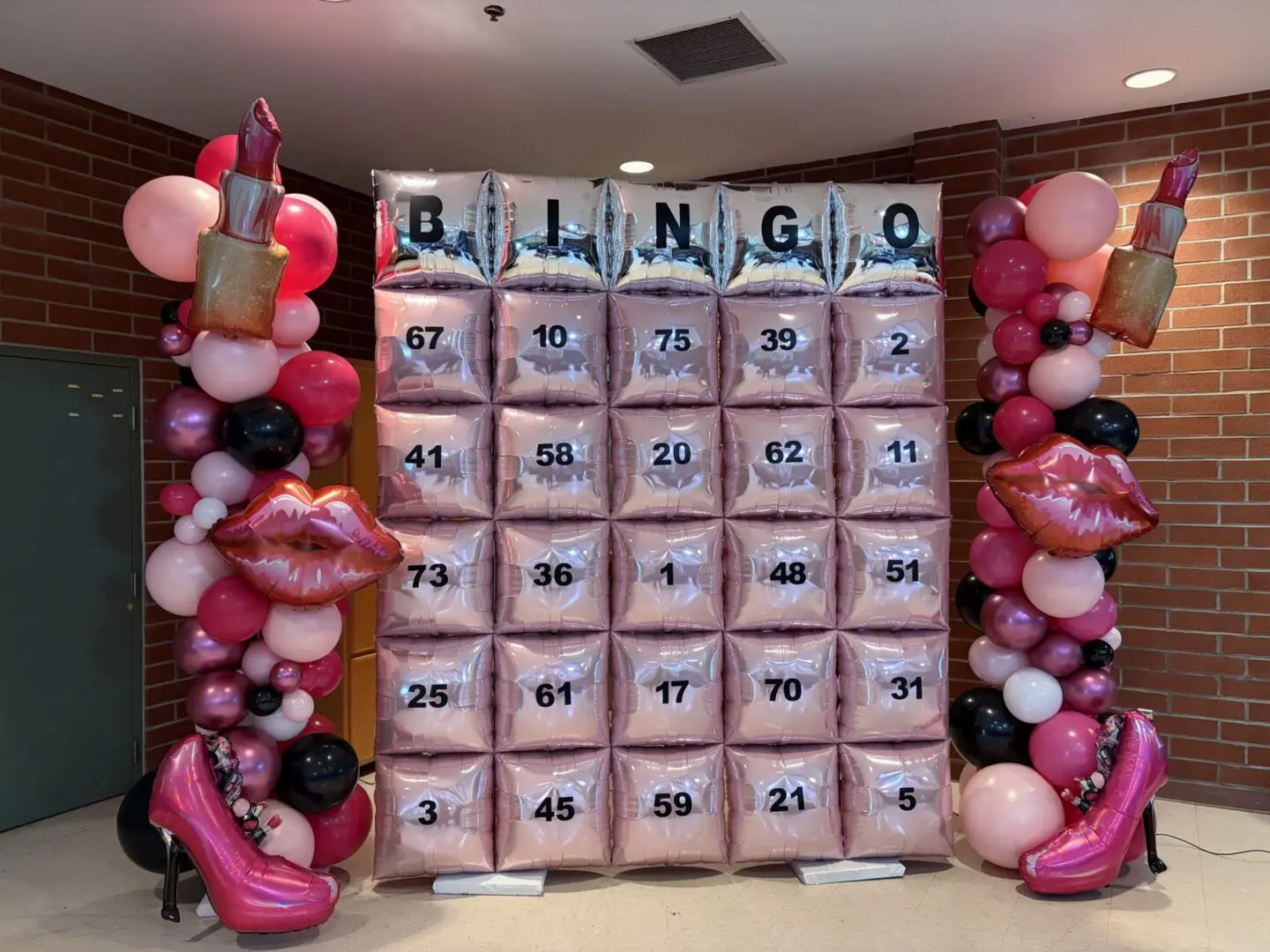 Pink-themed bingo balloon wall with lipstick decorations