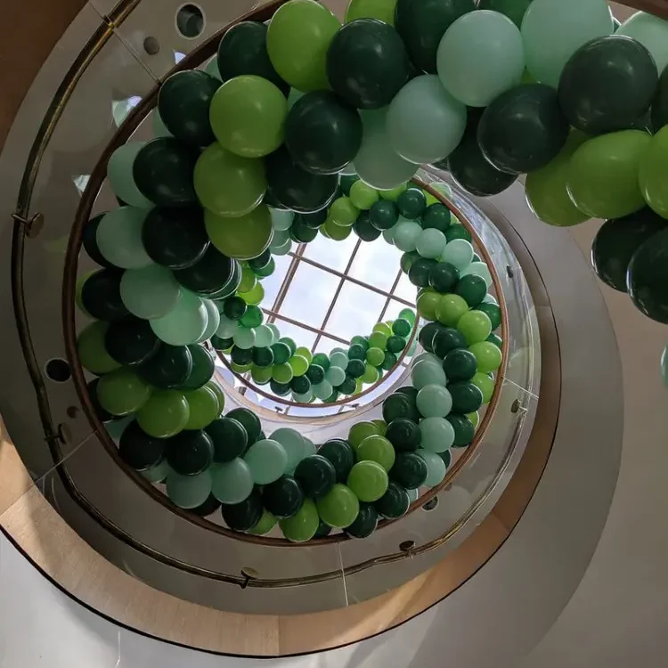 Organic balloon garland in forest green, lime, and mint wrapping a spiral staircase — Amazing Balloons by Gee